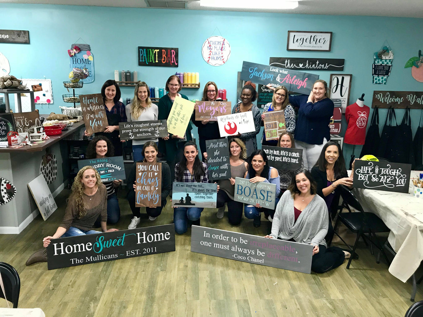 A group of women displaying their hand painted wooden decor they created on their own at a paint party in Cocoa, Fl.